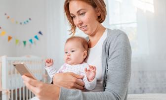 Mutter mit Baby schaut aufs Handy
